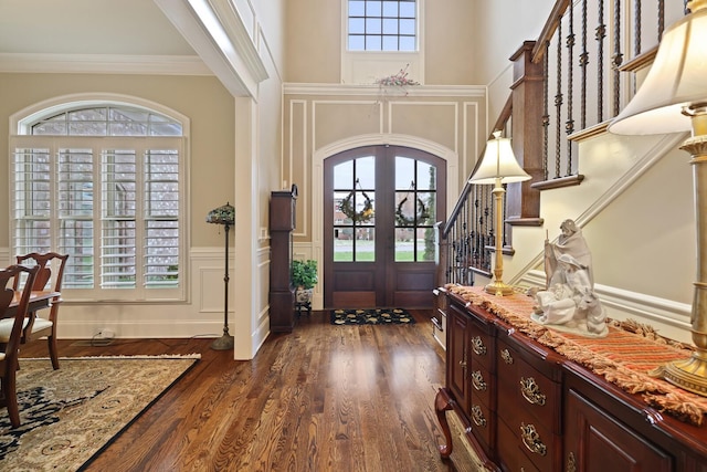 entryway featuring crown molding, french doors, dark wood-type flooring, and a high ceiling