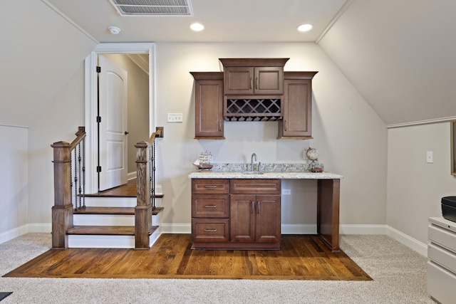 bar featuring light stone countertops, sink, vaulted ceiling, dark brown cabinets, and dark carpet