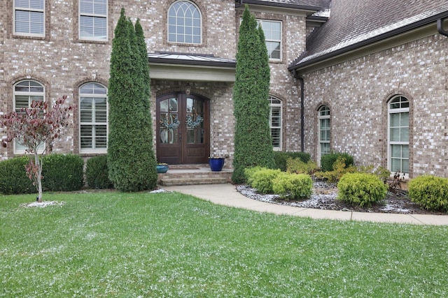 view of exterior entry with french doors and a yard