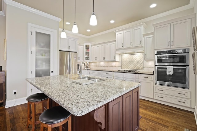 kitchen with dark hardwood / wood-style floors, a kitchen island with sink, sink, and appliances with stainless steel finishes