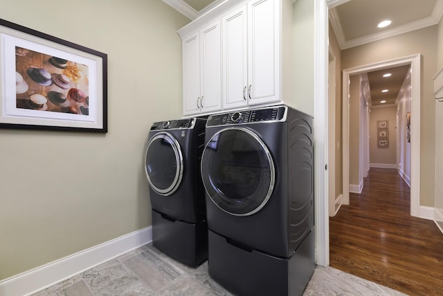 laundry area featuring washer and dryer, cabinets, ornamental molding, and light hardwood / wood-style flooring