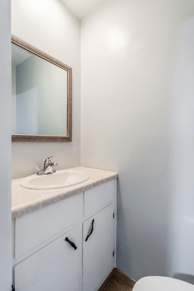 bathroom with hardwood / wood-style floors, vanity, and toilet