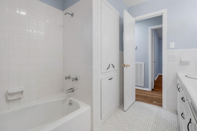 bathroom with vanity, hardwood / wood-style floors, tiled shower / bath combo, and tile walls