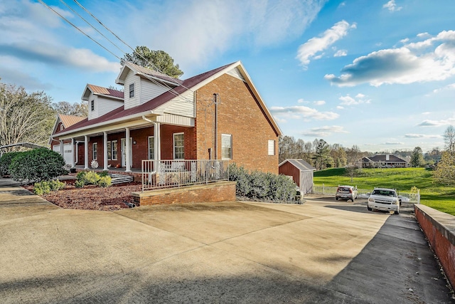 view of home's exterior with a porch and a storage shed