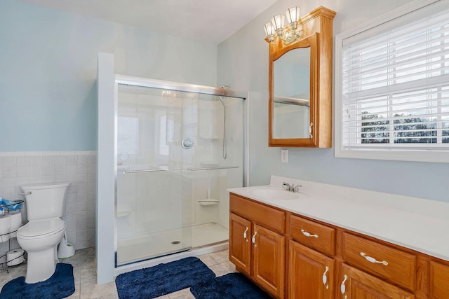 bathroom with vanity, a shower with door, tile patterned flooring, toilet, and tile walls