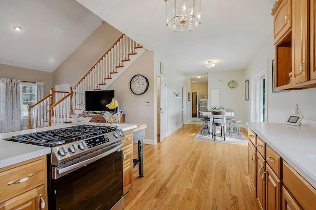 kitchen with hanging light fixtures, stainless steel gas range oven, a chandelier, lofted ceiling, and light hardwood / wood-style floors