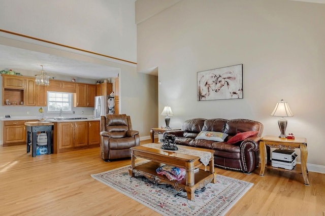 living room with light hardwood / wood-style floors, high vaulted ceiling, and a notable chandelier