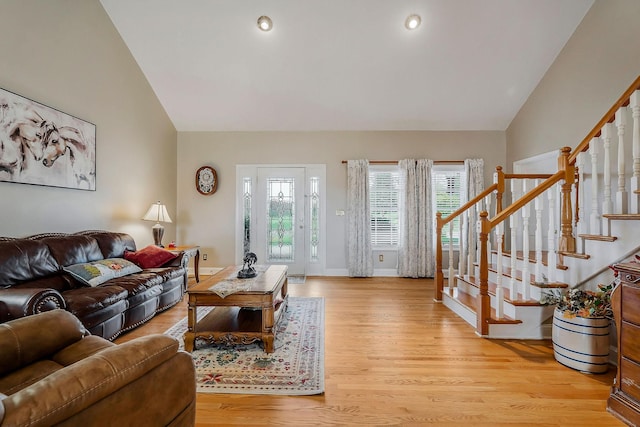 living room with light hardwood / wood-style floors and high vaulted ceiling