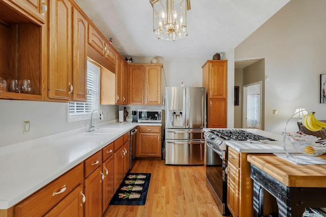 kitchen featuring sink, decorative light fixtures, light hardwood / wood-style flooring, a notable chandelier, and stainless steel appliances