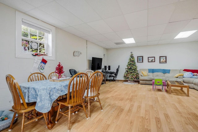 dining space featuring a drop ceiling and light hardwood / wood-style floors