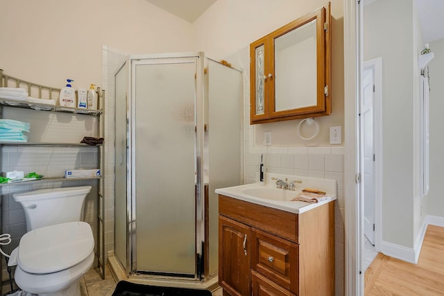 bathroom featuring vanity, toilet, an enclosed shower, and tile walls