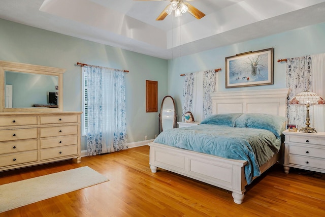 bedroom featuring a raised ceiling, ceiling fan, and light hardwood / wood-style floors