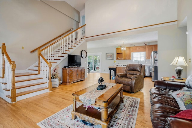 living room featuring light hardwood / wood-style floors, a high ceiling, and a notable chandelier