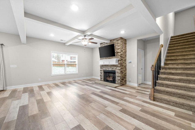 unfurnished living room featuring ceiling fan, beam ceiling, coffered ceiling, a fireplace, and light hardwood / wood-style floors