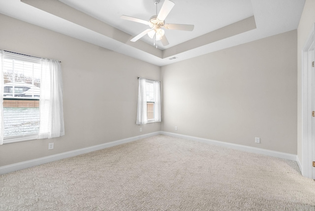 spare room featuring ceiling fan, carpet flooring, and a raised ceiling