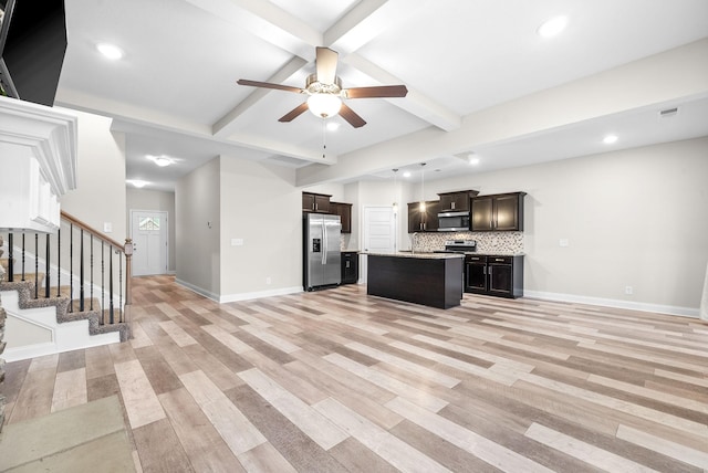 kitchen with appliances with stainless steel finishes, a kitchen island, ceiling fan, beam ceiling, and backsplash