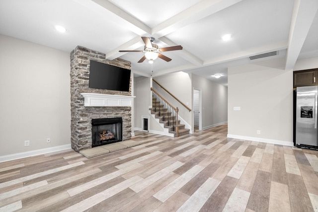 unfurnished living room featuring a fireplace, beamed ceiling, coffered ceiling, ceiling fan, and light hardwood / wood-style flooring