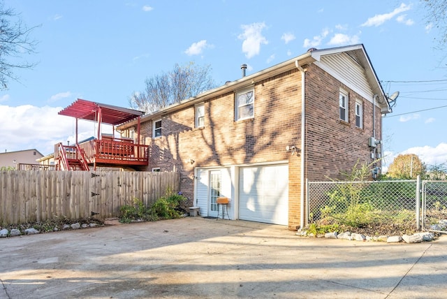 rear view of property with a wooden deck and a garage