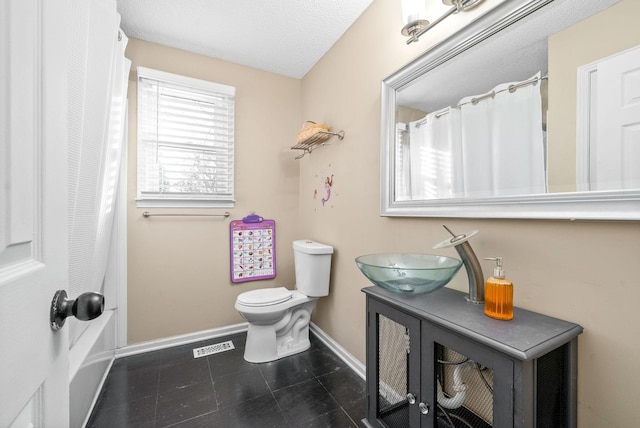 bathroom featuring a textured ceiling, vanity, and toilet