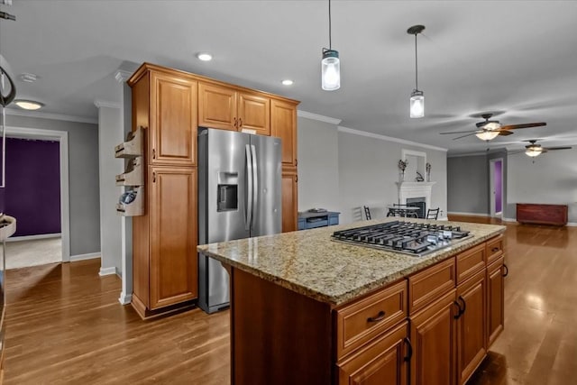 kitchen featuring a center island, crown molding, ceiling fan, appliances with stainless steel finishes, and dark hardwood / wood-style flooring