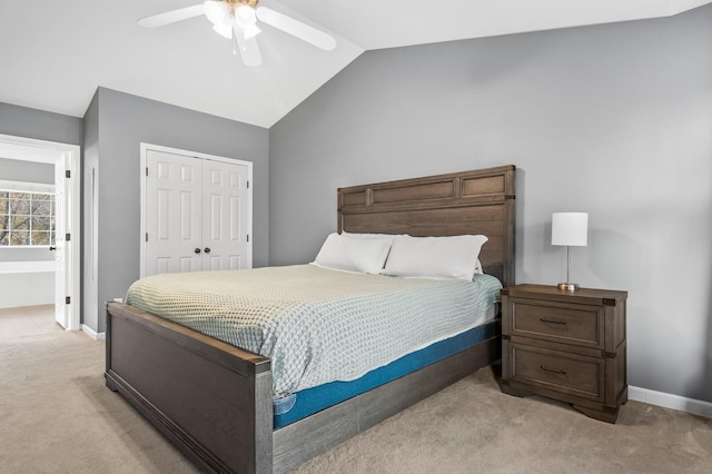 carpeted bedroom with ensuite bath, a closet, vaulted ceiling, and ceiling fan