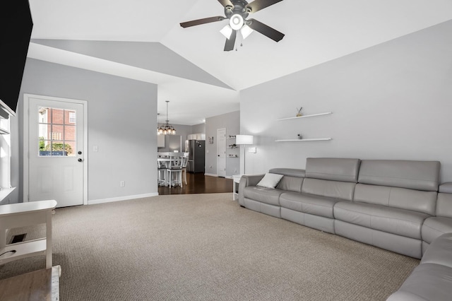 living room with ceiling fan with notable chandelier, dark carpet, and vaulted ceiling