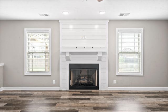 unfurnished living room featuring a wealth of natural light and dark wood-type flooring