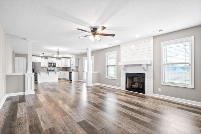 unfurnished living room featuring ceiling fan, a fireplace, a textured ceiling, and hardwood / wood-style flooring