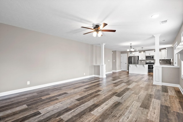 unfurnished living room with ornate columns, sink, dark hardwood / wood-style flooring, a textured ceiling, and ceiling fan with notable chandelier