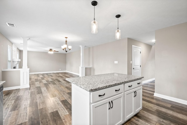 kitchen with decorative columns, white cabinets, pendant lighting, and dark hardwood / wood-style floors