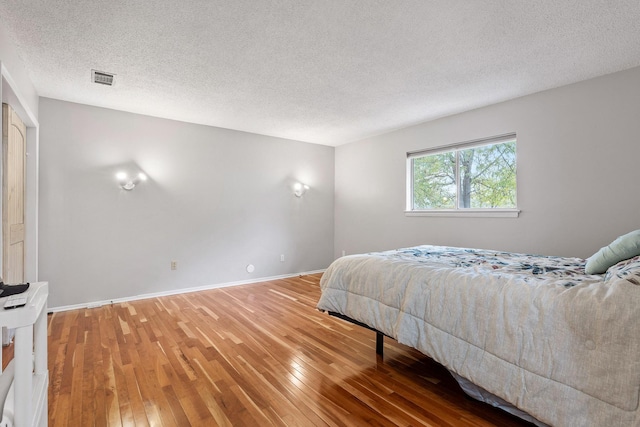 bedroom with hardwood / wood-style floors and a textured ceiling