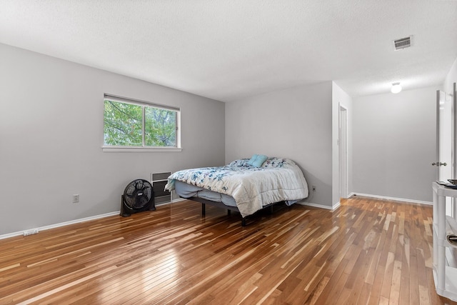 bedroom with hardwood / wood-style floors and a textured ceiling