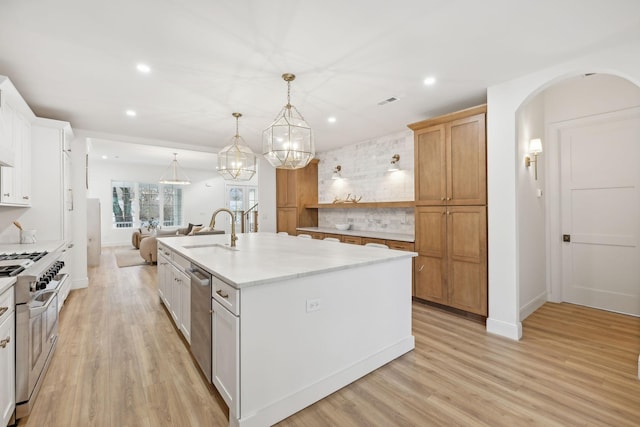 kitchen featuring pendant lighting, white cabinets, sink, an island with sink, and appliances with stainless steel finishes