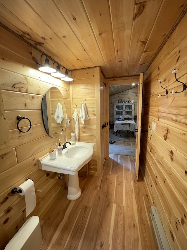 bathroom featuring hardwood / wood-style floors, a baseboard heating unit, wooden walls, and wood ceiling