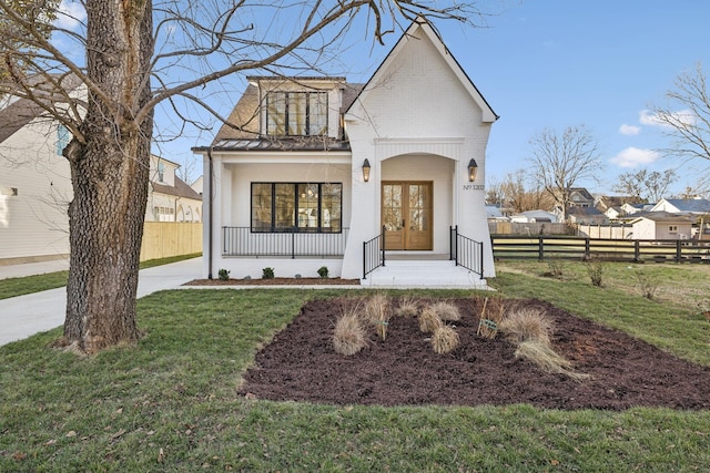 view of front of house with a porch, a front yard, and french doors