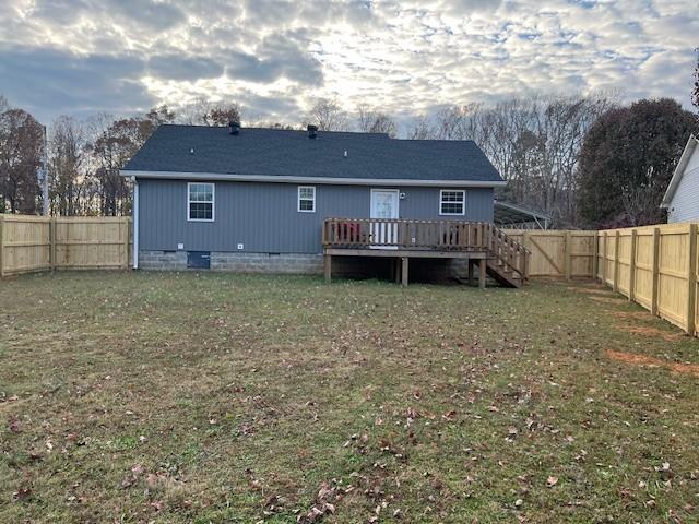 back of property with a wooden deck and a yard