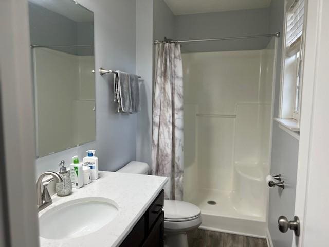 bathroom with a shower with shower curtain, hardwood / wood-style floors, vanity, and toilet