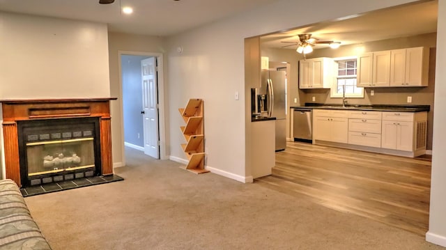 kitchen with ceiling fan, sink, light hardwood / wood-style flooring, white cabinets, and appliances with stainless steel finishes