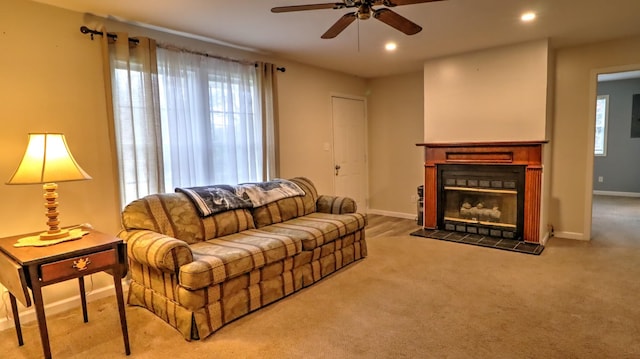 carpeted living room with ceiling fan and a fireplace