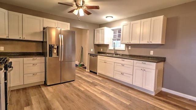 kitchen with white cabinets, appliances with stainless steel finishes, light hardwood / wood-style floors, and sink