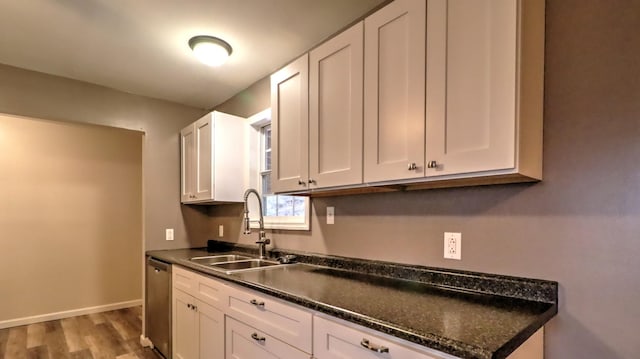 kitchen featuring hardwood / wood-style floors, dishwasher, dark stone counters, white cabinets, and sink