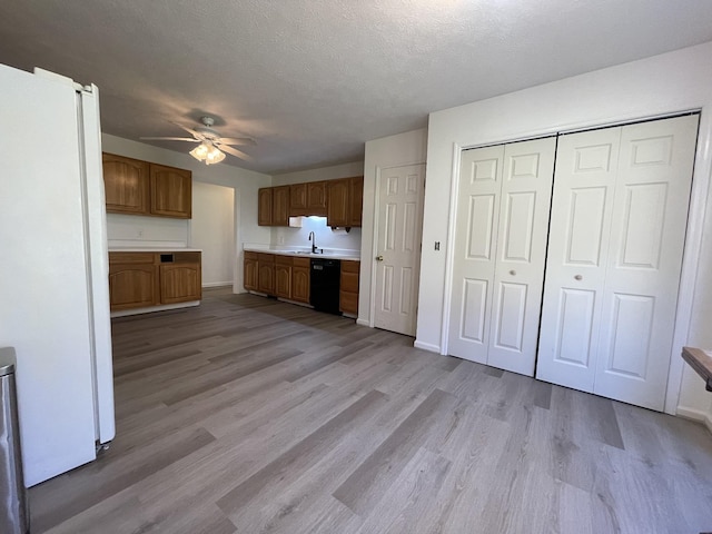 kitchen featuring light wood-type flooring, sink, white fridge, and black dishwasher