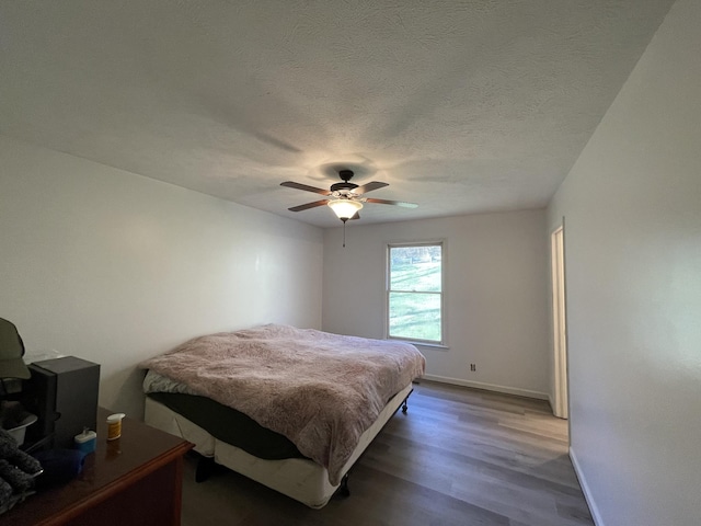 bedroom featuring ceiling fan, a textured ceiling, and dark hardwood / wood-style floors