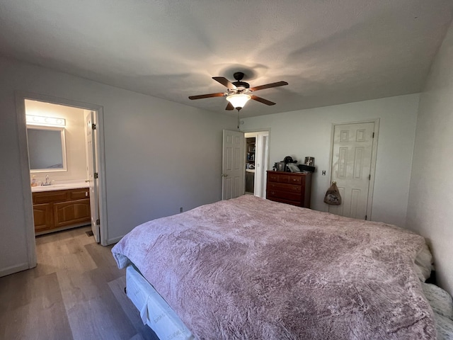 bedroom featuring ceiling fan, ensuite bath, sink, and light hardwood / wood-style floors