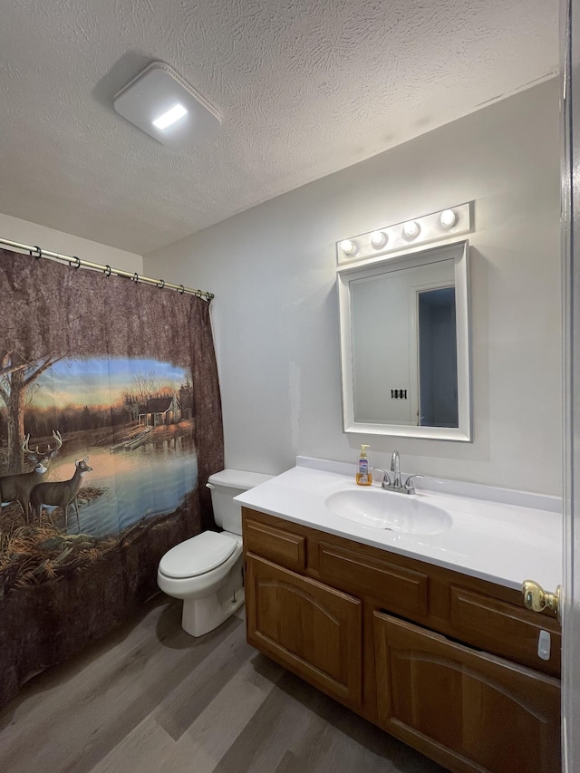 bathroom featuring hardwood / wood-style floors, toilet, vanity, and a textured ceiling