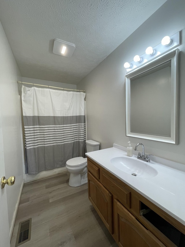 bathroom with hardwood / wood-style floors, toilet, vanity, and a textured ceiling