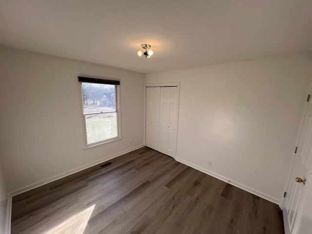 unfurnished bedroom with dark wood-type flooring and a closet