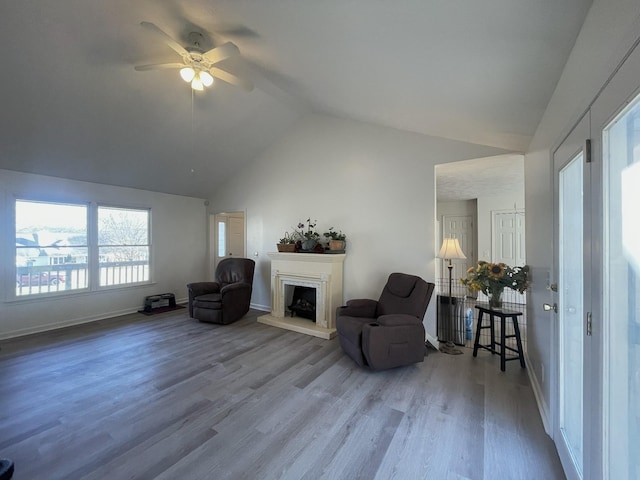 living area with ceiling fan, wood-type flooring, and vaulted ceiling