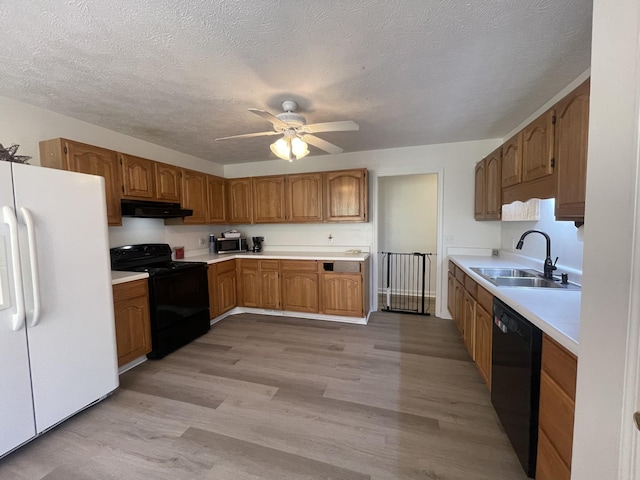 kitchen featuring ceiling fan, a textured ceiling, black appliances, light hardwood / wood-style flooring, and sink