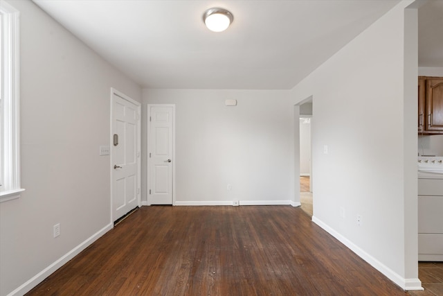 unfurnished room featuring dark wood-type flooring and washer / dryer